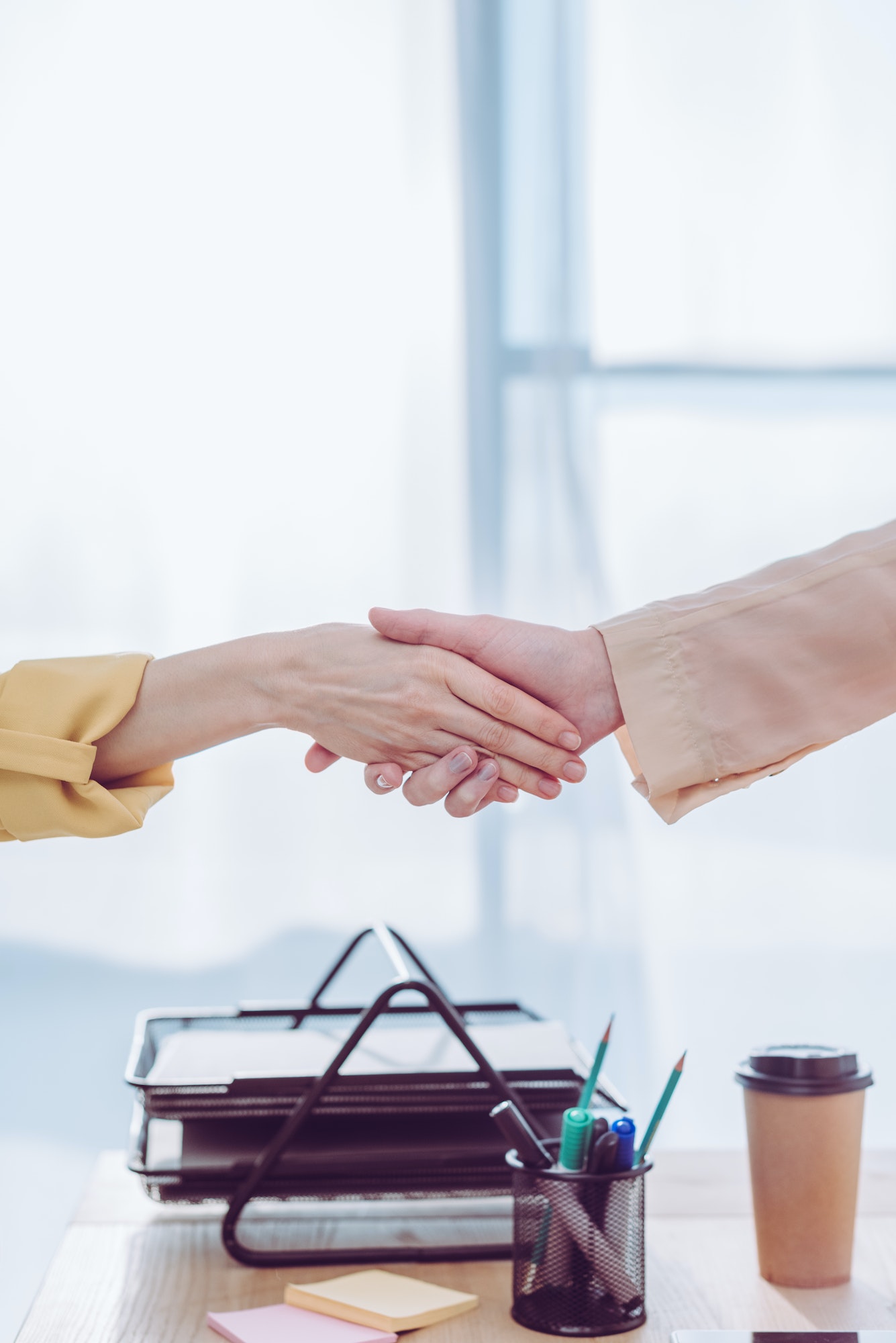 cropped view of recruiter and female employee shaking hands in office